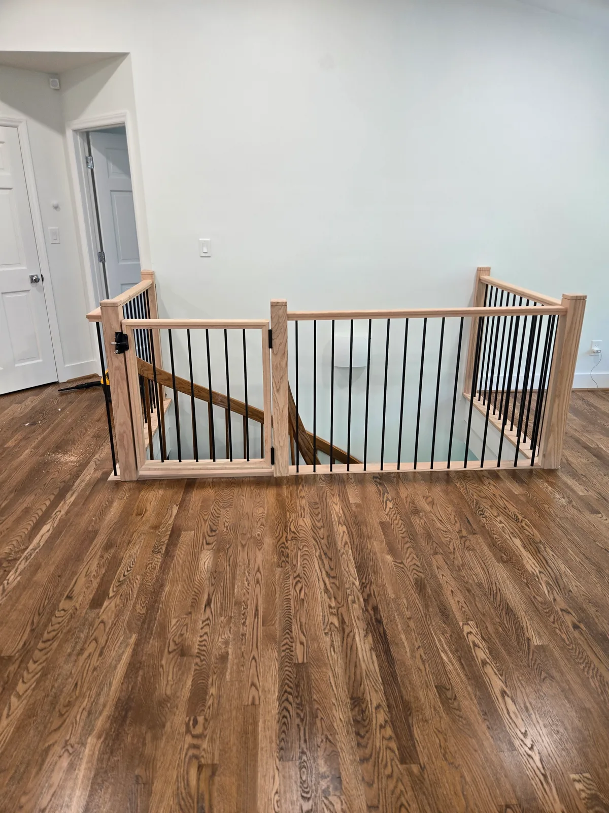 Interior stair railing after replacement with wood rails and black iron balusters